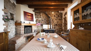 Un coin repas rustique avec une nappe à carreaux, des murs en pierre, des poutres en bois et une cheminée.