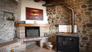 Un mur de pierre, une cheminée, un poêle et un tableau.