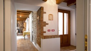 Un couloir avec un mur en pierre, une porte en bois et un sol carrelé.