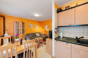 Un espace de vie compact comprenant un coin repas, un canapé, une cuisine avec un évier et un meuble vitré.