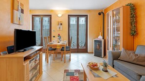 A living room with a TV, dining table, chairs, and a sofa.