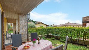 A patio with a table set for two, surrounded by stone walls and a view of a vineyard.