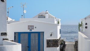 Een smalle straat met witte gebouwen, een blauwe deur en een bordje met de tekst 'Casa de la Mar'.