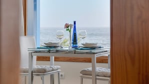 Een tafel met een vaas, wijnglazen en borden, met uitzicht op zee.