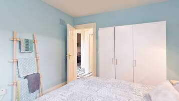 A bedroom with a bed, a wardrobe, and a wooden ladder with towels.