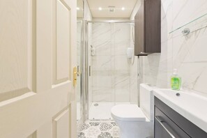 A bathroom with a glass shower enclosure, a toilet, and a sink with a soap dispenser. - The Manor Suite at Moyglare Manor (Maynooth)