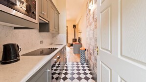 A narrow kitchen with a black and white checkered floor, a built-in stove, and a coffee maker. - The Manor Suite at Moyglare Manor (Maynooth)