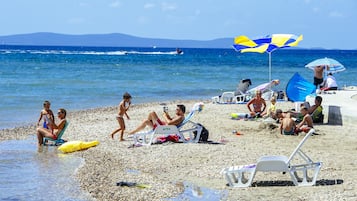 Une plage où des gens se prélassent au soleil et se baignent, et où l’on aperçoit un jet ski sur l’eau.
