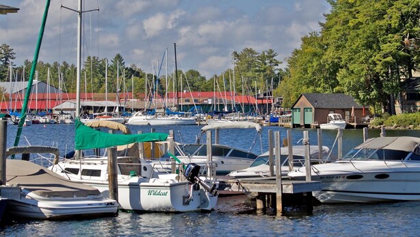 Een jachthaven met diverse boten afgemeerd, een klein gebouw met een rood dak en een groen dak boven een boot.