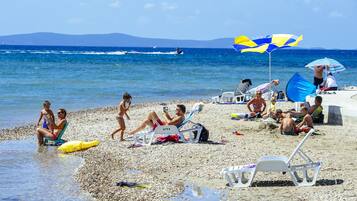 Una playa con gente tomando el sol y nadando, y un jet ski en el agua.