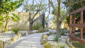A stone pathway leading through a garden with rocks, plants, and a wooden fence.