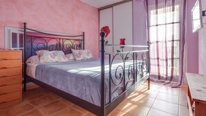 Quarto com cama, penteadeira e janela com cortinas.