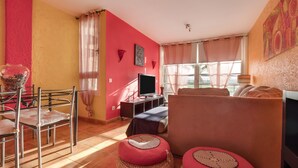 Uma sala de estar com televisão, sofá e poltrona.