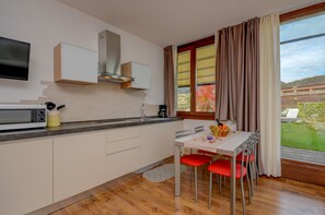 Una cucina moderna con zona pranzo, televisione a schermo piatto e un'ampia finestra con tende.