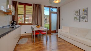 A modern kitchen with a dining area, a sofa, and a large window with curtains. - Holiday Apartment "GeoResort B6" with Panoramic Views and Shared Pool (Tremosine)