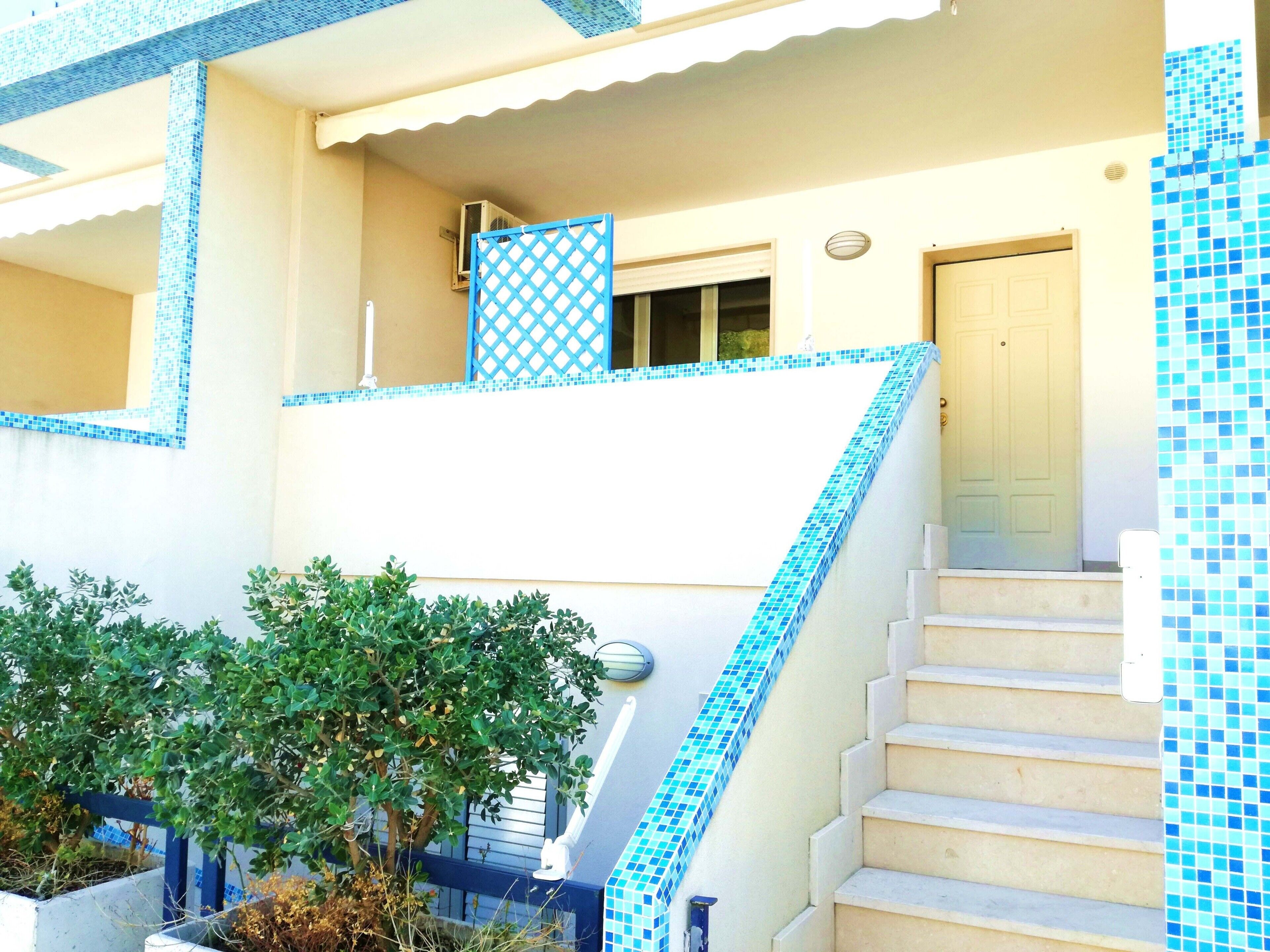 A building with a staircase leading to a balcony, a door, and a window.