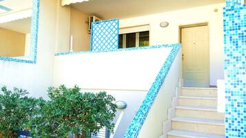 A building with a staircase leading to a balcony, a door, and a window.