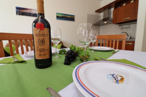 A dining table with a bottle of wine, wine glasses, and a plate with a decorative emblem.