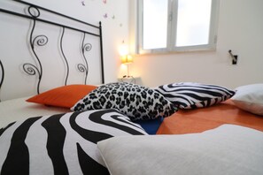 A bed with patterned pillows, a bedside lamp, and a window with a view.