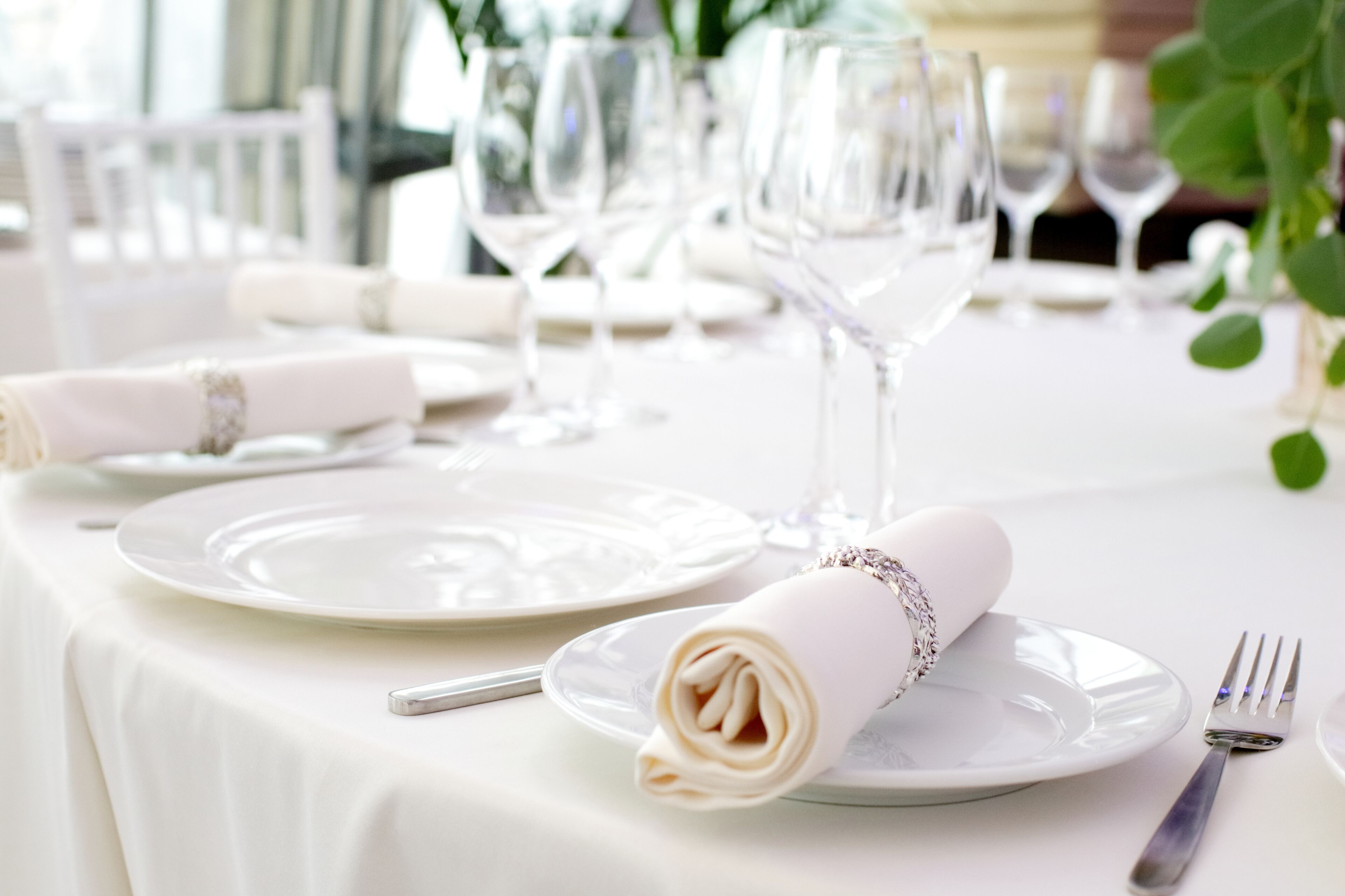 Una mesa dispuesta con platos blancos, servilletas dobladas y cubiertos, lo que sugiere un ambiente de comedor formal.
