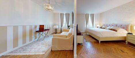 A bedroom with a bed, a desk, a chair, a small table, and a mirror.