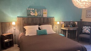 A neatly arranged bedroom with a bed, bedside tables, a small round table, and a chair. - Chambre d'hôtes Bleus Matines (Caveirac)
