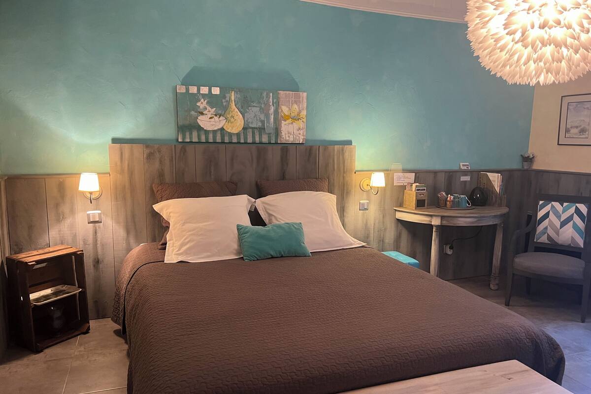 A neatly arranged bedroom with a bed, bedside tables, a small round table, and a chair.