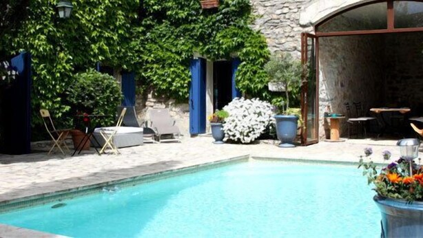 A pool area with a stone patio, lounge chairs, and potted plants. - Chambre d'hôtes Bleus Matines (Caveirac)