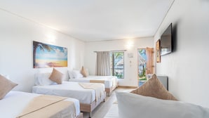 A hotel room with three beds, a sofa, a TV, and a painting of a beach scene. - Hotel La Fragata Coveñas (Coveñas)