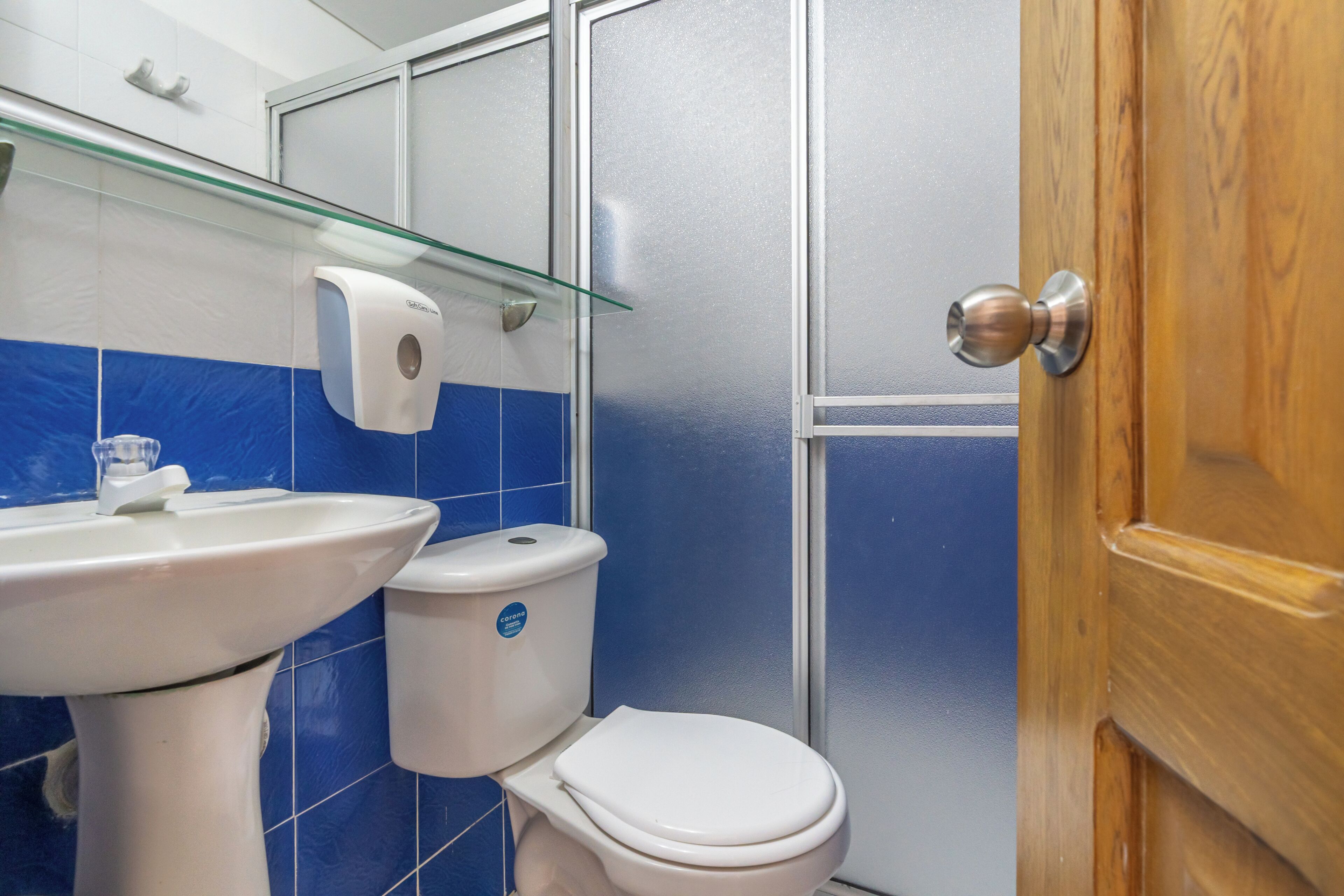 A bathroom with a white sink, a toilet, and a glass shower enclosure.