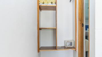 A wooden wardrobe with shelves and a hanging rod, a small safe, and a metal hook.