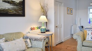 A cozy living room with a sofa, a small table with a lamp, and a door leading to another room. - 3 bedroom accommodation in Broadstairs (Broadstairs)