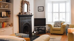 A living room with a fireplace, a television, and two armchairs. - 3 bedroom accommodation in Broadstairs (Broadstairs)