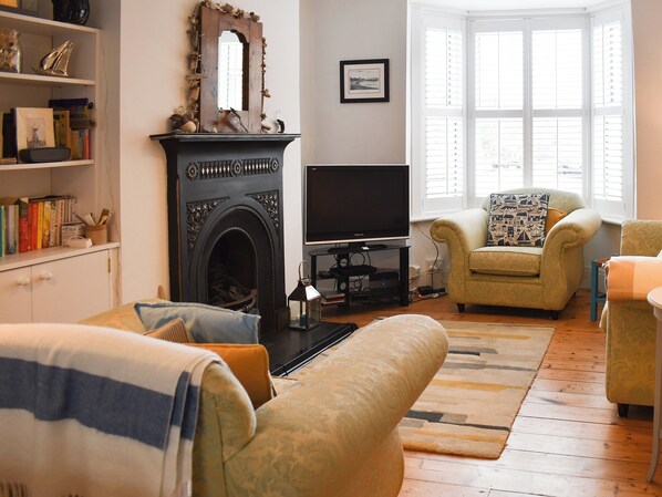 Una sala de estar con chimenea, televisor y dos sillones.