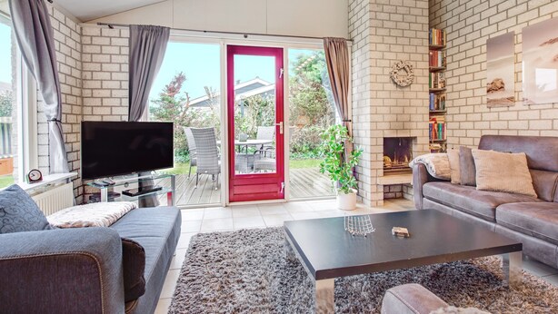Una sala de estar con televisión, sofá, mesa de centro y chimenea.