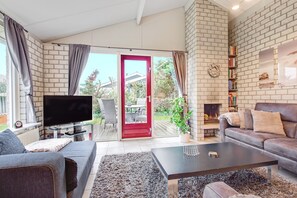 A living room with a television, sofa, coffee table, and fireplace. - Cosy Holiday Home Petten aan Zee with Pool, Garden, Terrace & Wi-Fi (Petten)