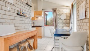 Una cocina con encimera de madera, sillas blancas y pared de ladrillo.