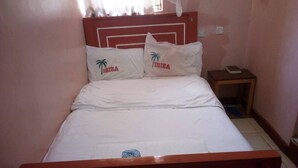 Un letto con biancheria bianca e due cuscini con la scritta 'IBIZA' e motivi a palma.