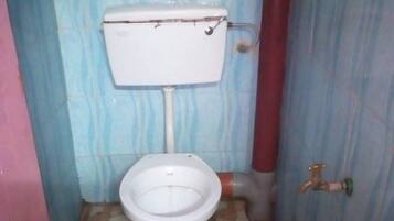 A small bathroom with a toilet, a wall-mounted sink, and a shower area.
