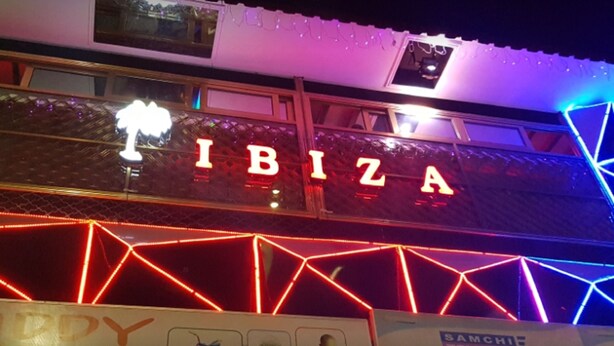 Un edificio con un neon che riporta la scritta “IBIZA” e una insegna per “SANCHEZ TELECOM”.