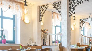 A restaurant interior with wooden chairs, tables, and hanging light fixtures. - Nordstern Restaurant & Pension (Gingst)