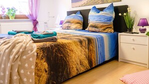 A bedroom with a bed, a nightstand, a lamp, and a window with curtains. - Nordstern Restaurant & Pension (Gingst)