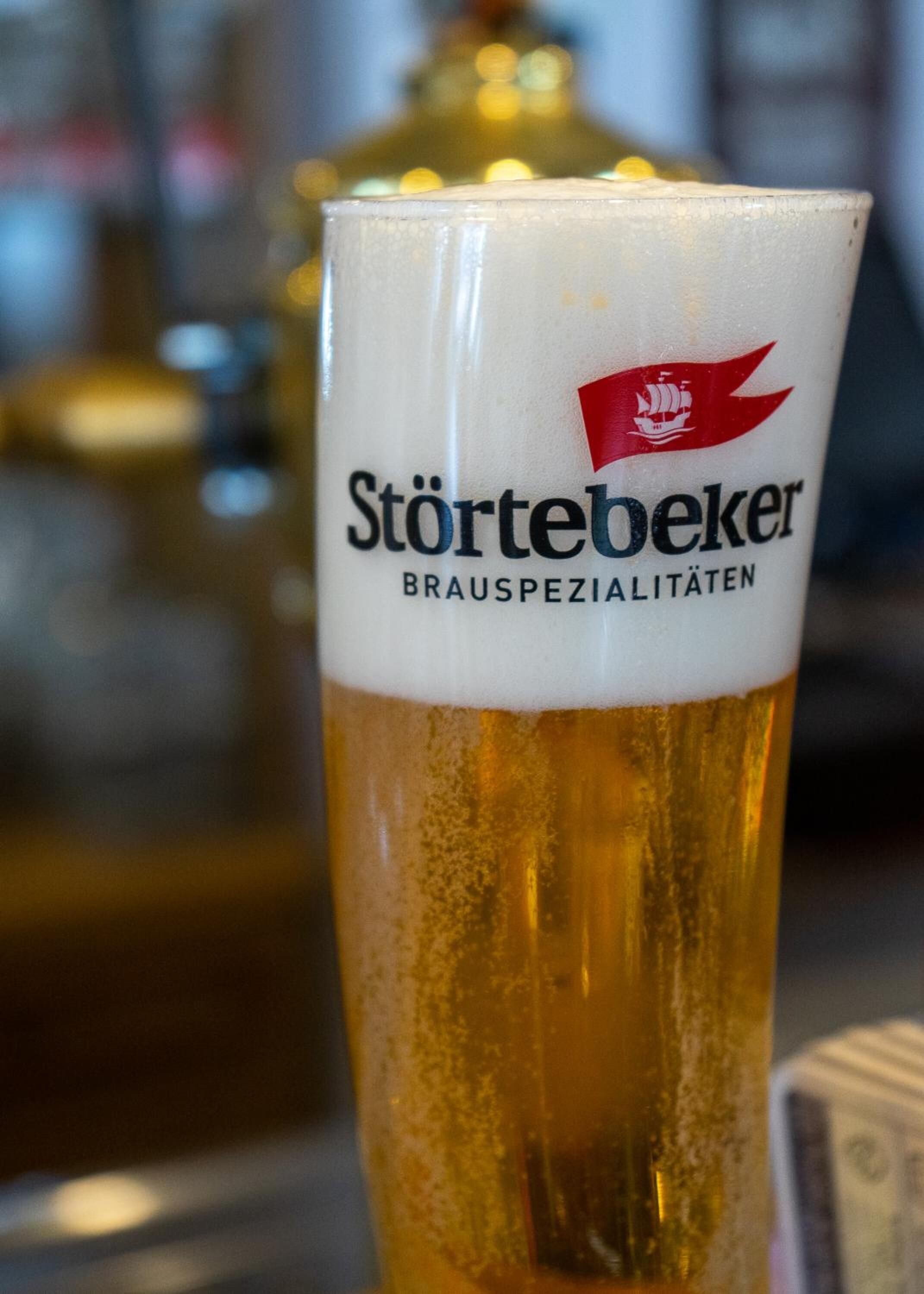 Un verre de bière dont l’étiquette porte l’inscription « Störtebeker Brauspezialitäten ».