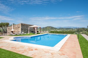 A swimming pool with a stone wall, a gazebo, and a view of mountains. - Traditional Mallorcan Villa "S'Era de Son Roig" with Garden, Pool & Wi-Fi (Sant Joan)