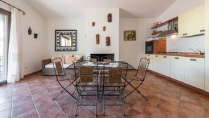 Un comedor con una mesa redonda y sillas, un sofá, una chimenea y armarios de cocina.