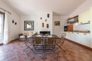 Un coin repas avec une table ronde et des chaises, un canapé, une cheminée et des meubles de cuisine.