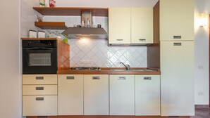 Una cocina con estufa, horno, pileta y alacenas.