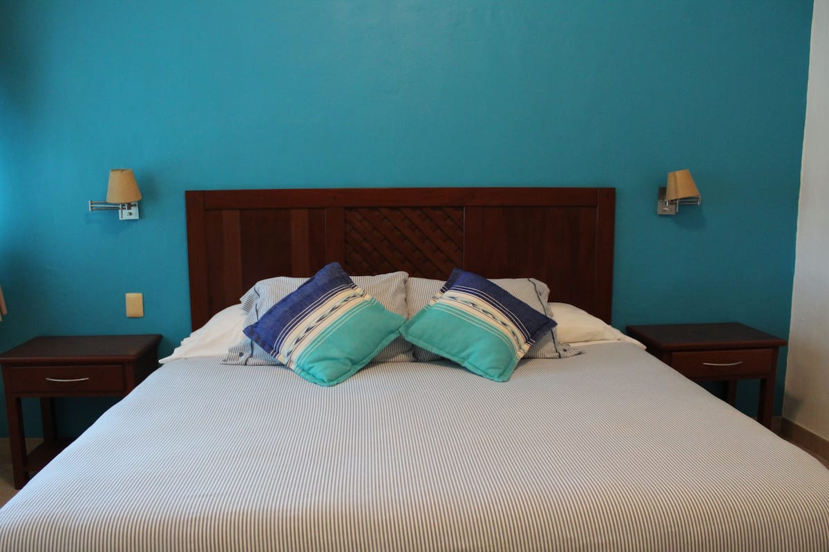 A bed with striped bedding, two nightstands, and wall-mounted lamps.