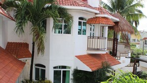A residential building with a swimming pool, surrounded by palm trees and a red-tiled roof. - Casa Mandarina Cozumel (Cozumel)