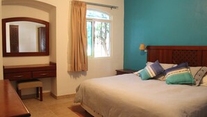 A bedroom with a bed, a desk, a chair, a mirror, and a window with curtains. - Casa Mandarina Cozumel (Cozumel)